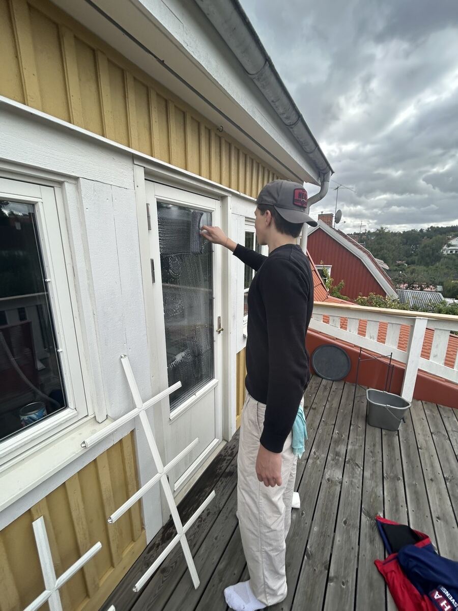 En av oss torkar av en altandörr och fönsterparti med trasa på en uteplats
