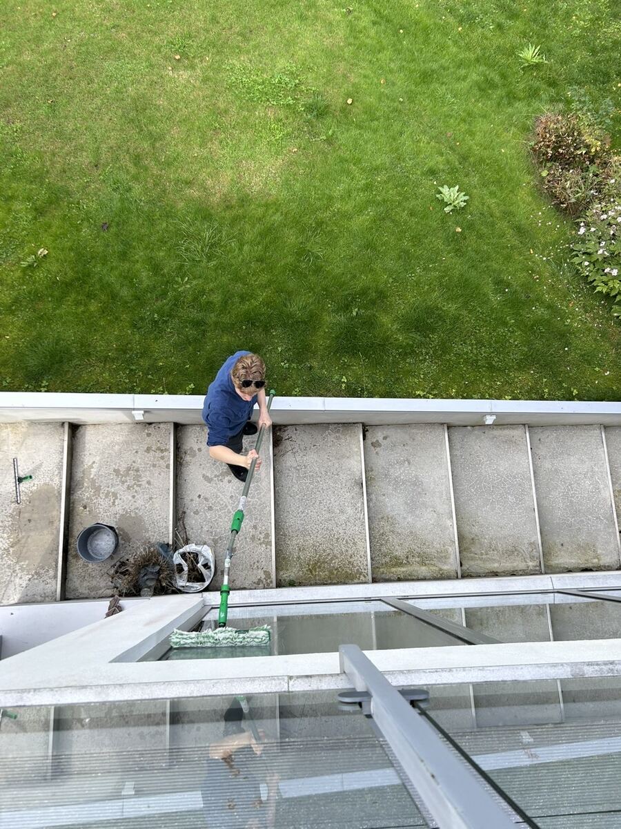 Ovanifrån, en av oss putsar ett takfönster med rentvattenstång